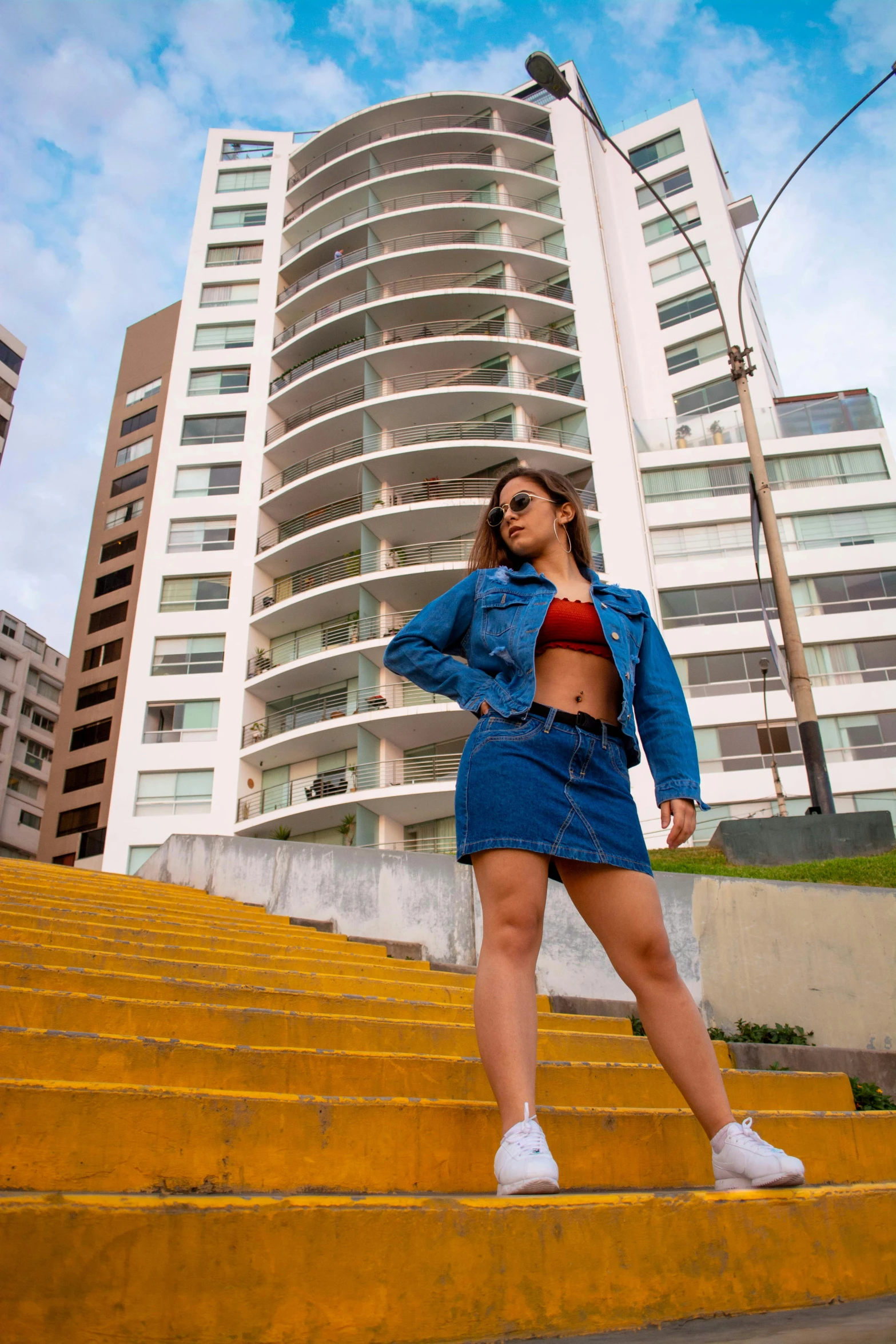 the woman is posing on the steps near some tall buildings