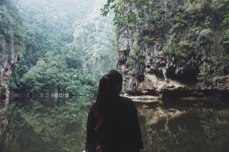 person standing at the edge of a pool surrounded by green trees