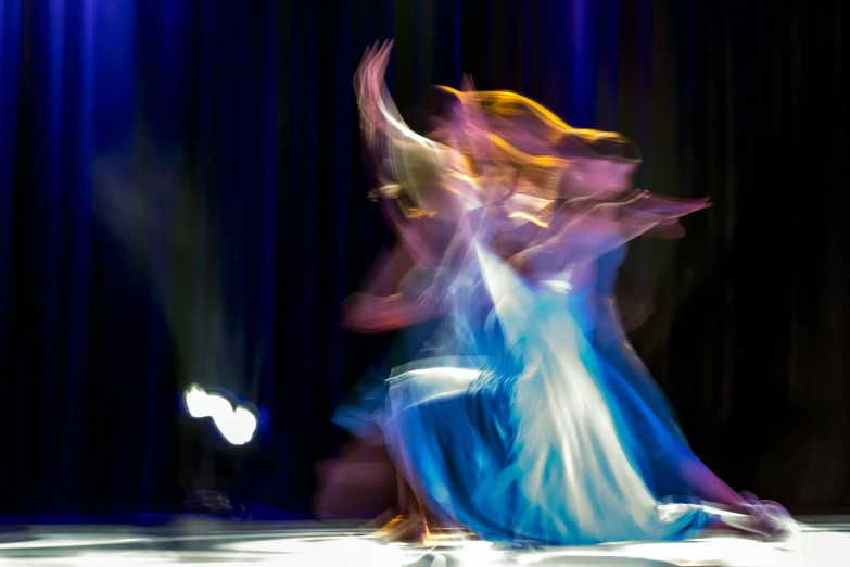 a woman is dancing with a man wearing a long dress