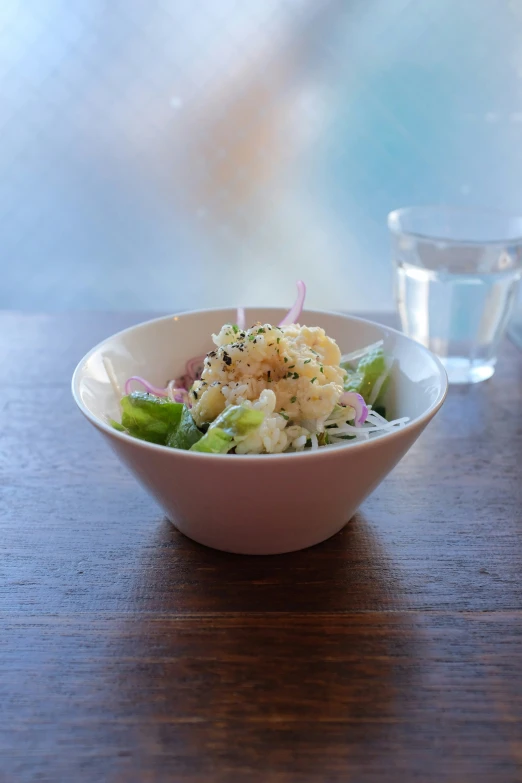 a bowl full of shrimp and broccoli sitting on a table next to a glass