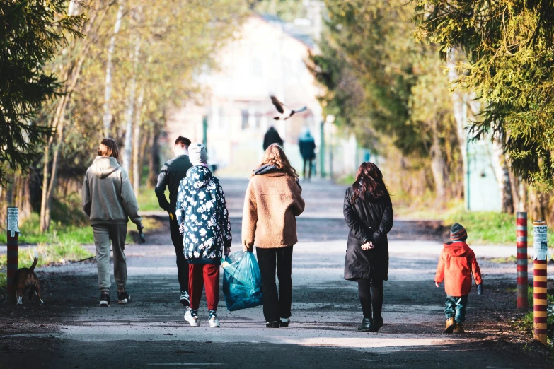 a group of people walk down a tree lined street