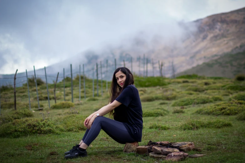 a woman in blue pants sitting on top of grass