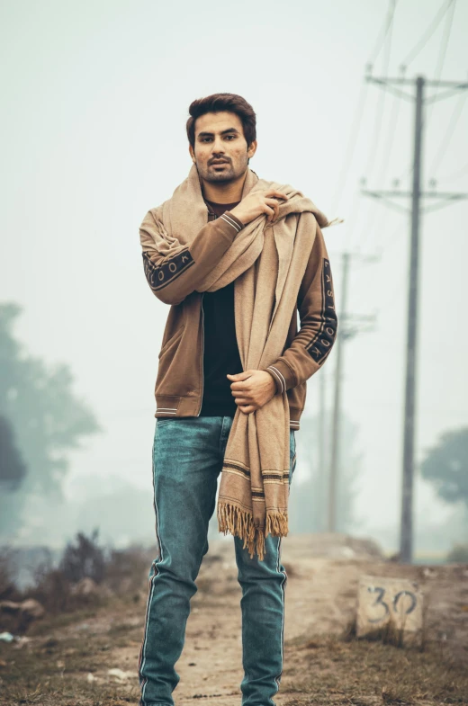 a male with a brown coat and scarf standing in the dirt