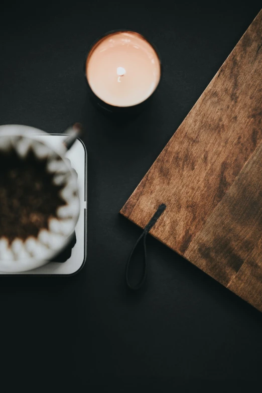 a cup of  chocolate sitting on a tray next to a small candle