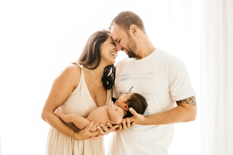 a couple holds their baby while the baby sits between his hands