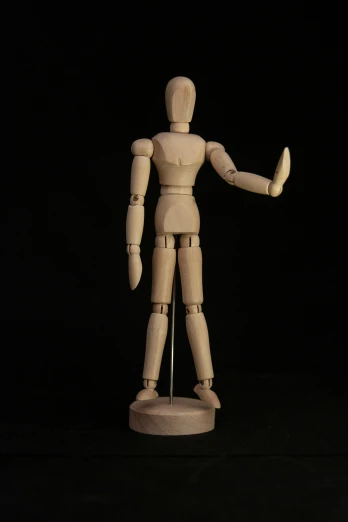 a wooden dummy on a black background holding soing