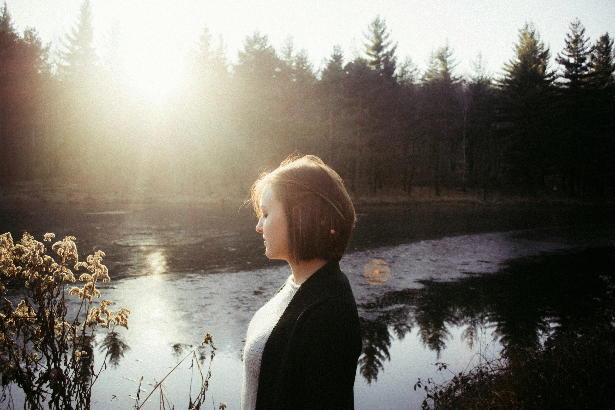 a woman looking out at the river during sunset