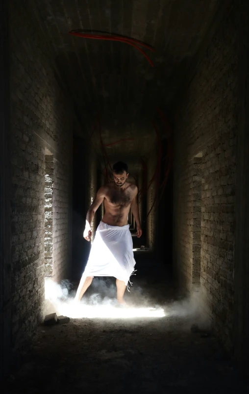 man in white shirt and no - shirt holding a knife in an alley