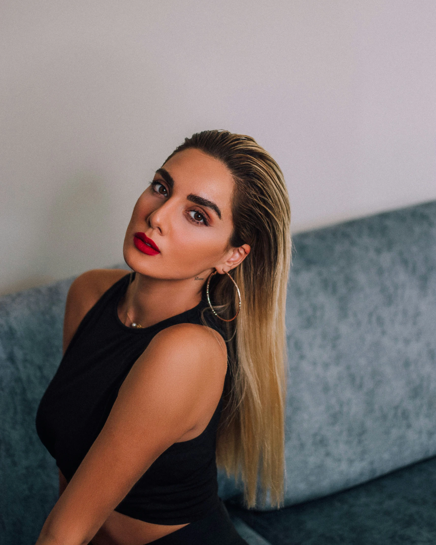 young woman with red lips sitting on a gray couch