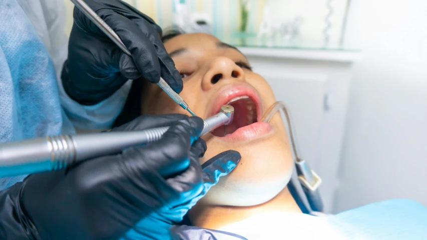 the woman is getting her teeth checked by the dentist