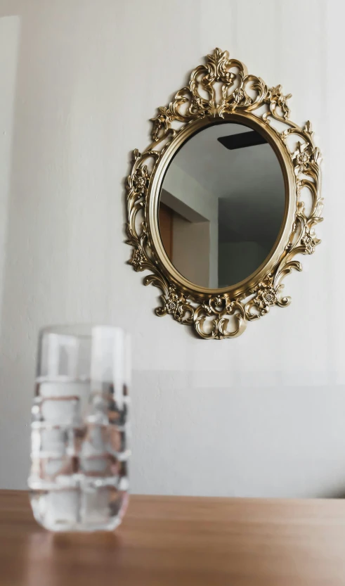 a gold framed mirror next to two glasses