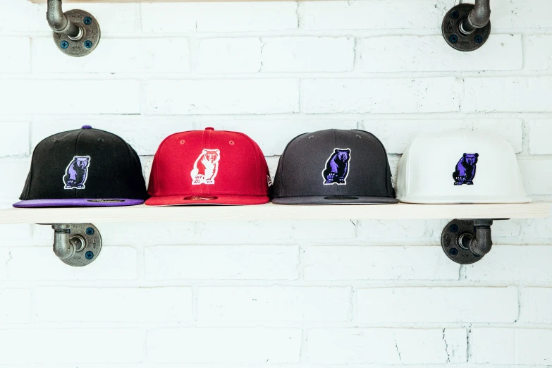 four hats sitting on top of shelves in front of a white brick wall