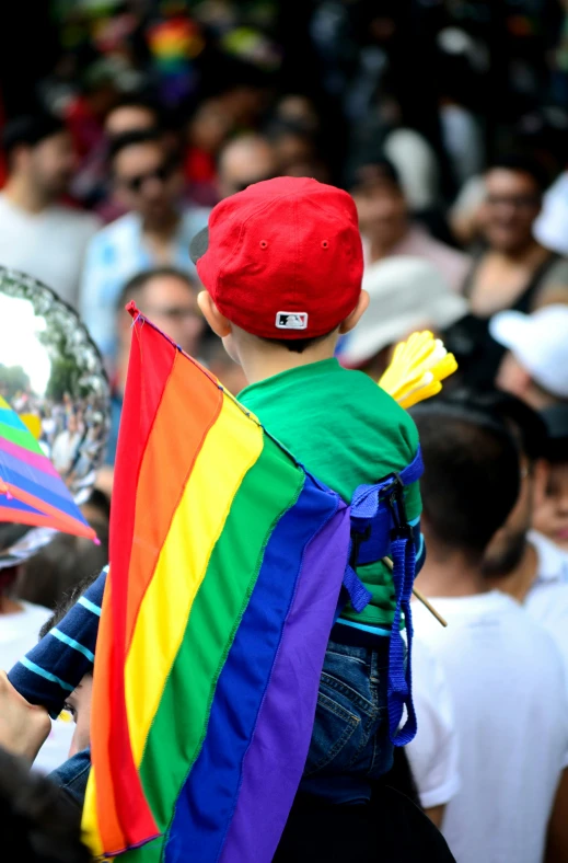 a boy dressed in a rainbow flag with a mirror