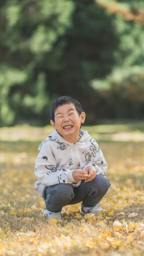 a boy squatting down laughing in a field