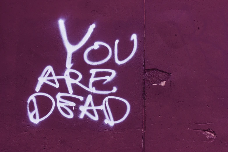 graffiti that says you are dead written on a wall