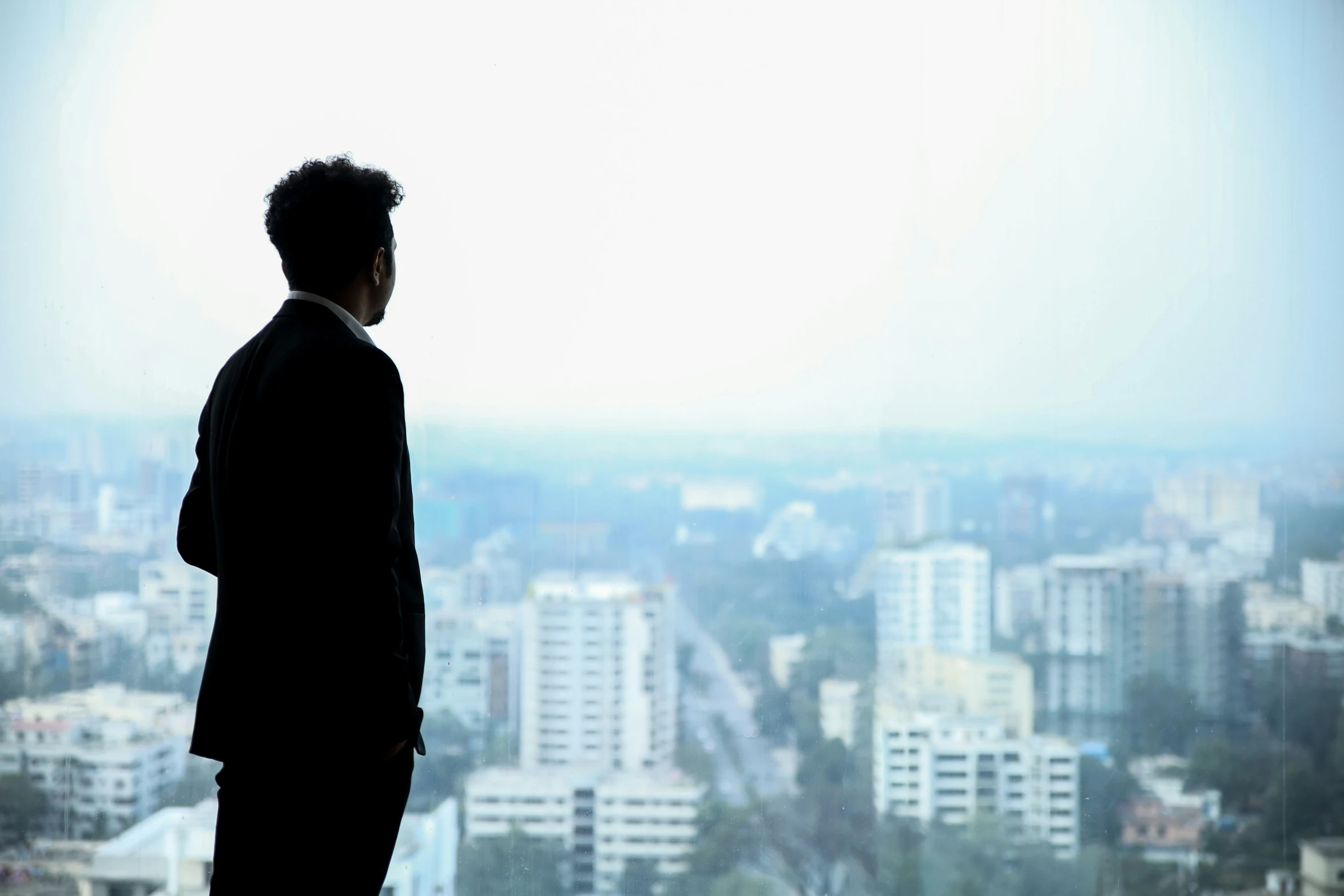 man looking out on the cityscape while standing in front of a window