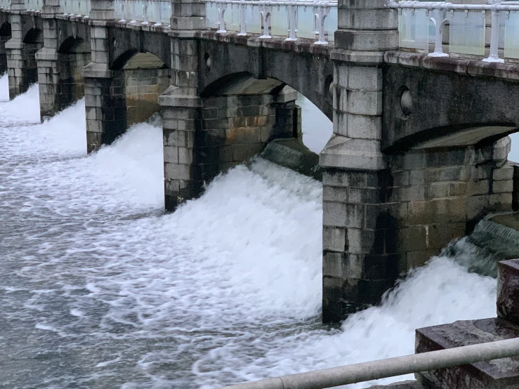 an old stone bridge in winter, with foam coming out from underneath