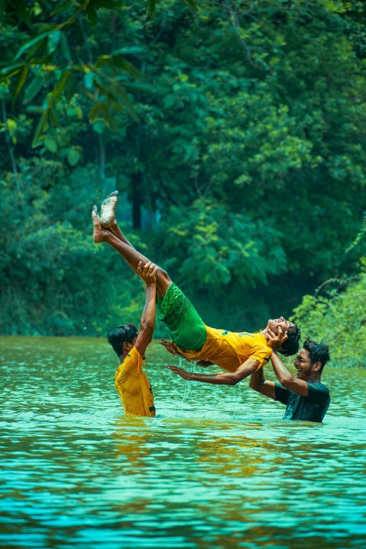 two people jump into a body of water in front of a forest