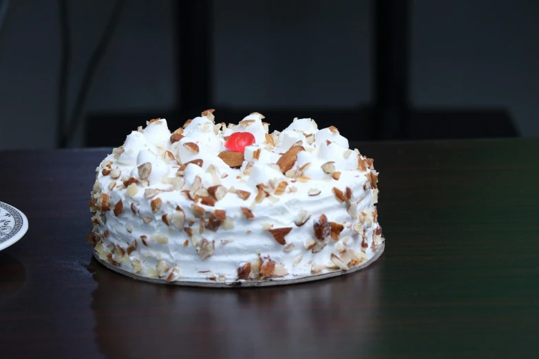 a large white cake with white frosting and nuts