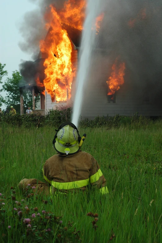 a firefighter wearing a helmet sprays water on a building that's blazing