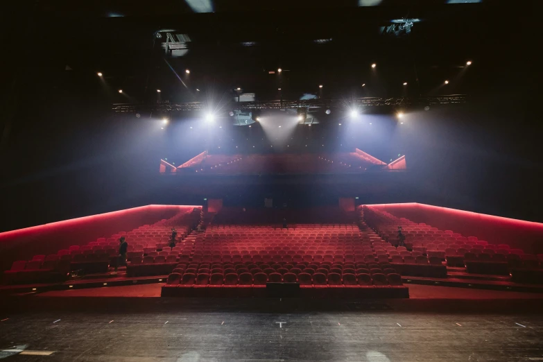 a dark auditorium with red seats and bright lights