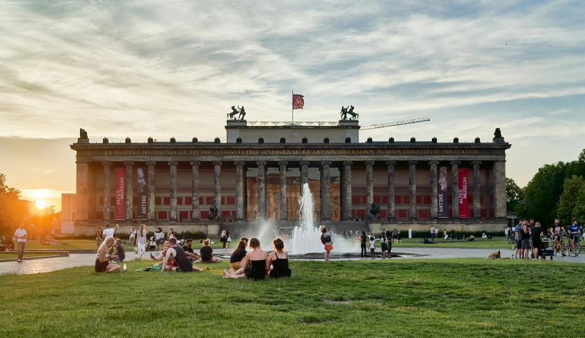 a large building with fountain and people sitting around in the grass