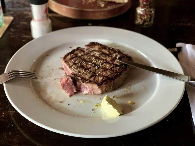 a piece of meat on a white plate with a knife and fork