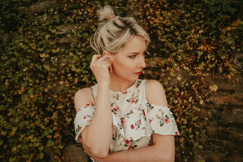 a woman posing next to leaves with her head resting on her hand