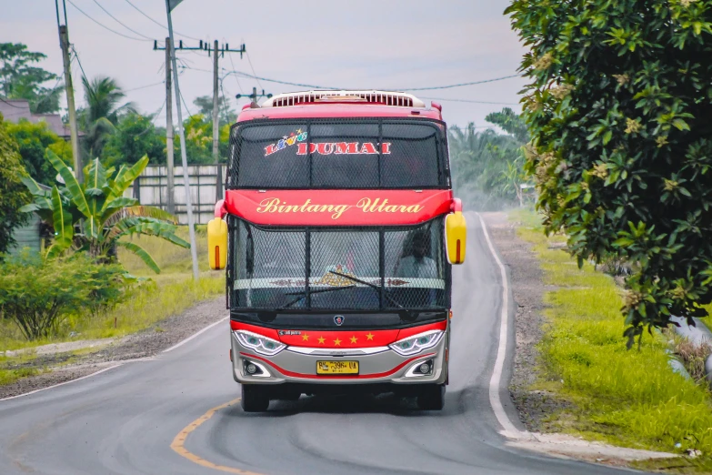 red and yellow passenger bus driving down a country road