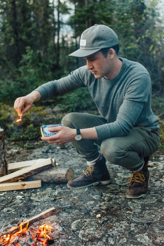 the man is lighting the fire while sitting in front of him