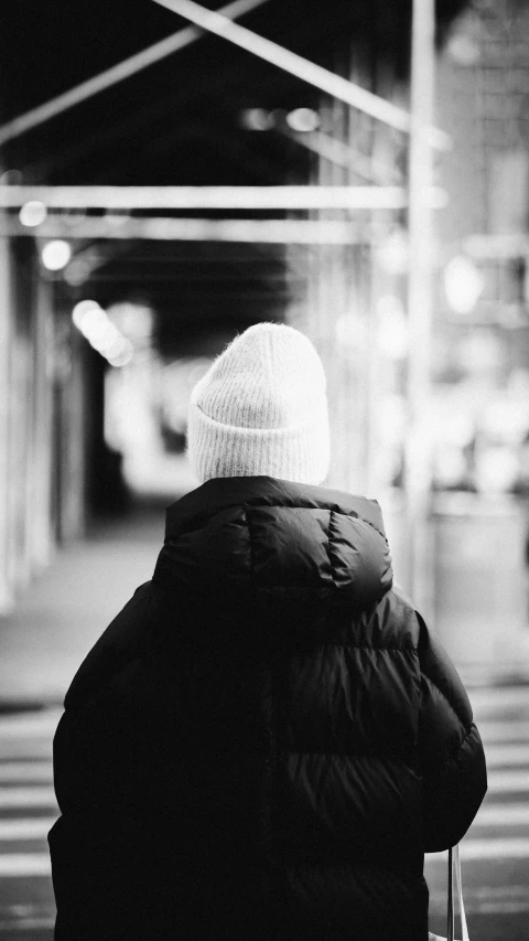 a man in a black coat is walking towards the building