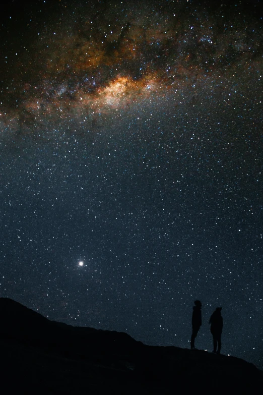 two people under the night sky looking up at stars