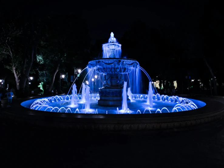 the colorful light is shining around the fountain