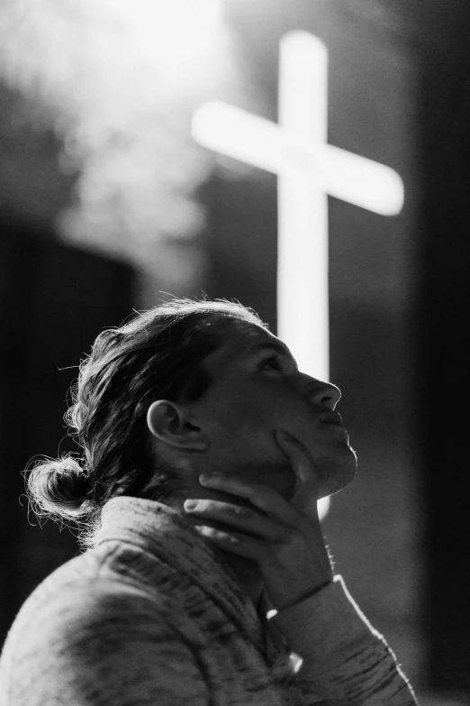 a woman looks at the cross in the dark