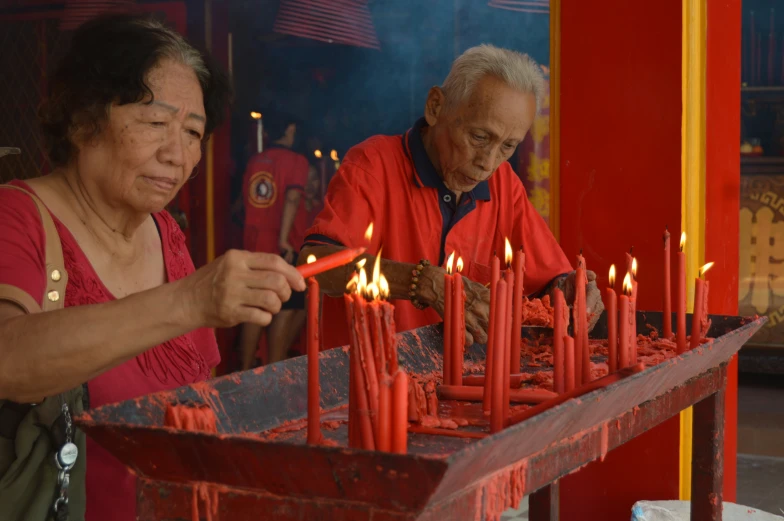 an elderly man and woman lights candles together