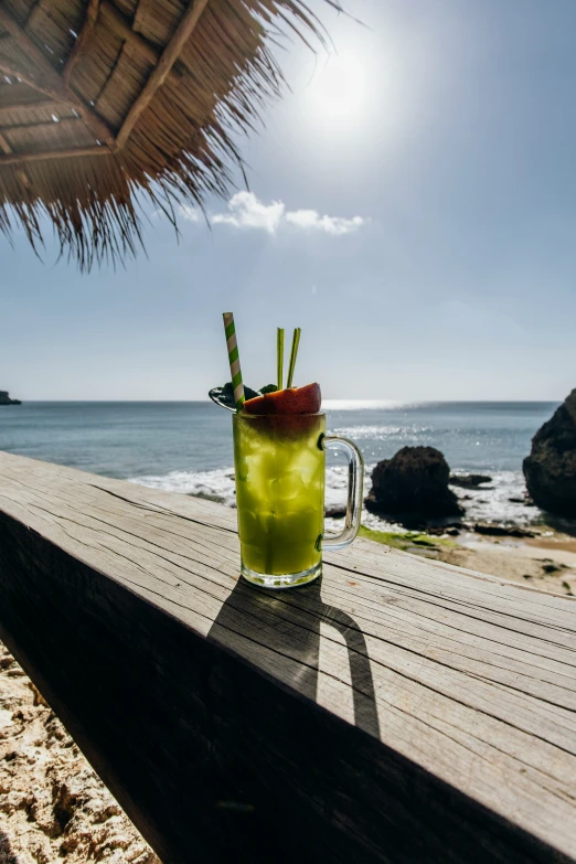 a cold drink in a cup next to the beach