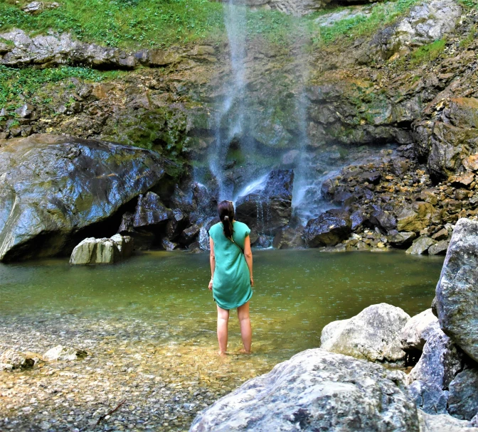 there is a girl that is standing in front of a waterfall