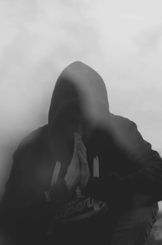 a hooded man kneeling down in the smoke