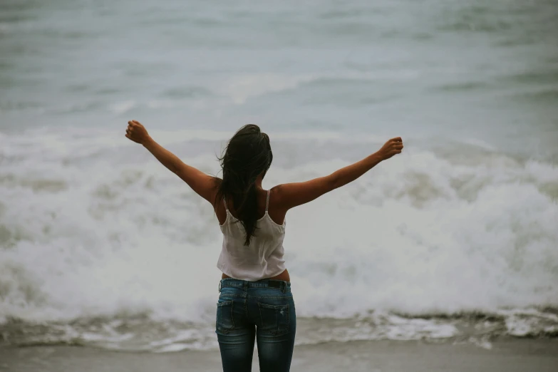 a woman standing on top of a beach near the ocean