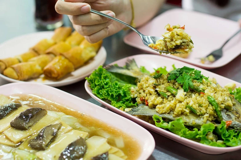 a person eating food at a table with plates of vegetables