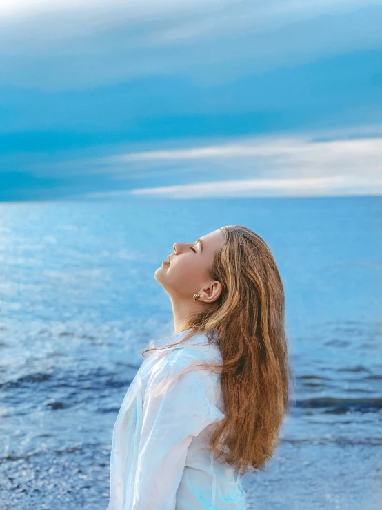 a girl standing on a beach in front of the ocean