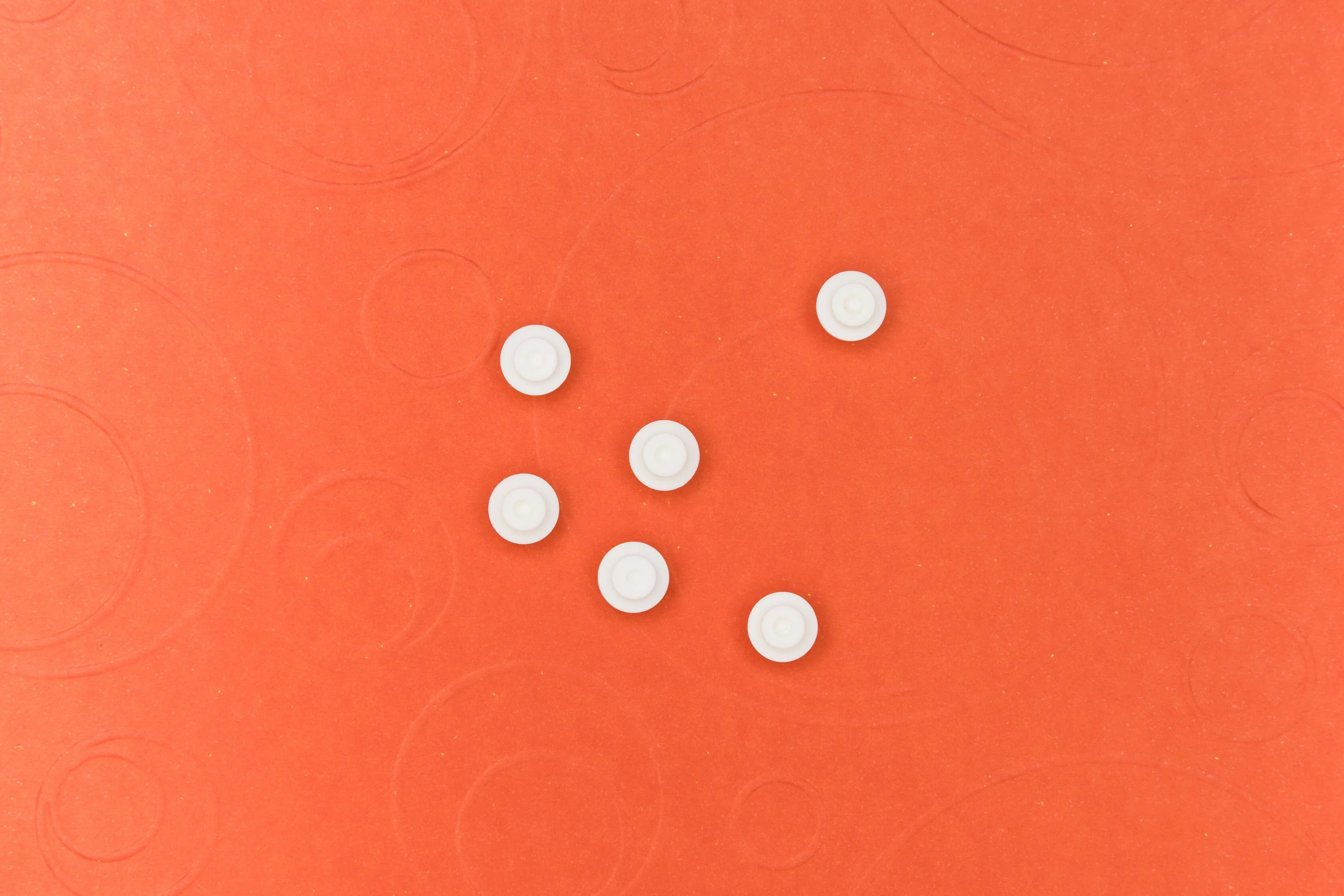 four small white circles lay on an orange background