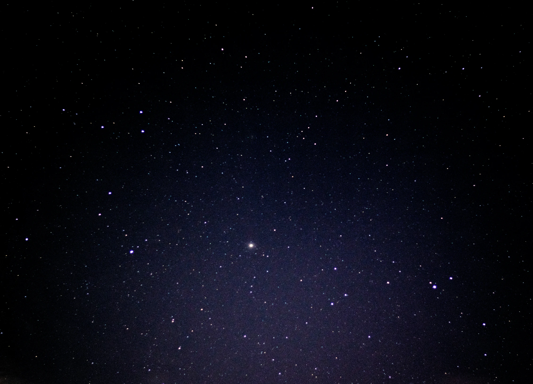 the night sky shows some stars above a hill