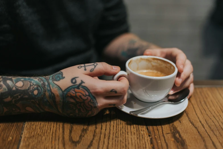 a man holding a white coffee cup and saucer