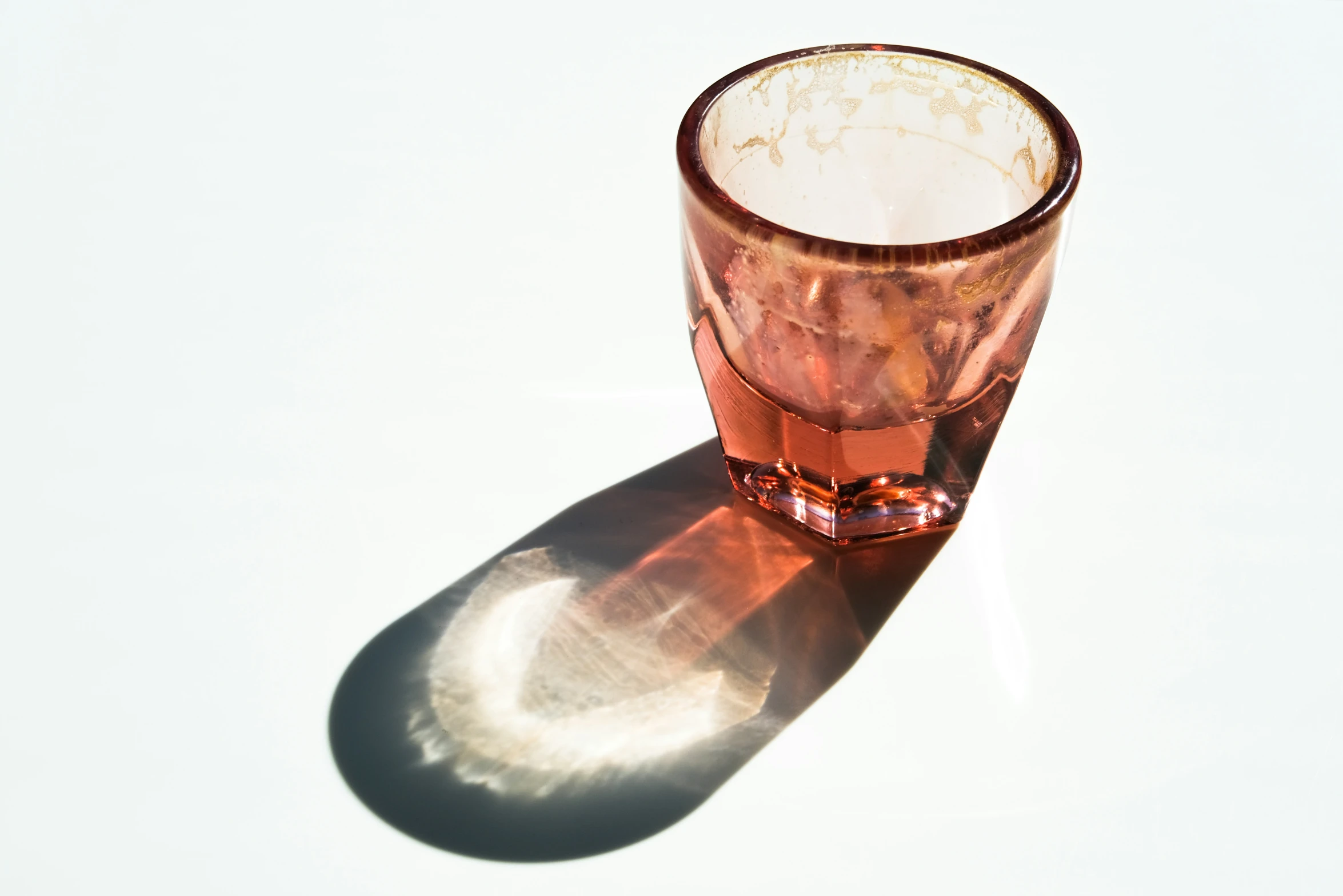 a dirty glass sitting in the sun on the table