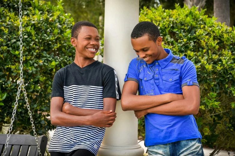 two young men laughing while leaning against a column