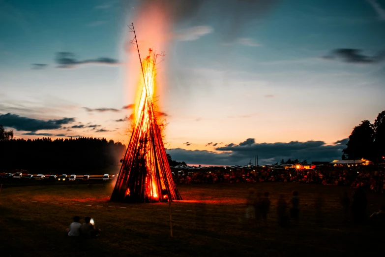 people are standing around a tall structure that's burning