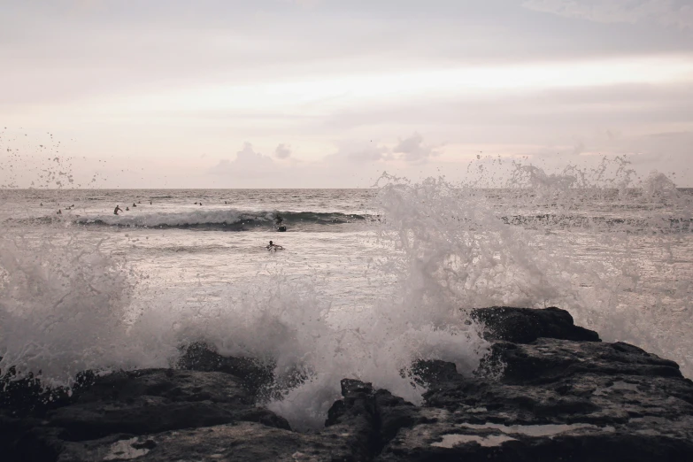 people in the ocean water near a rocky beach