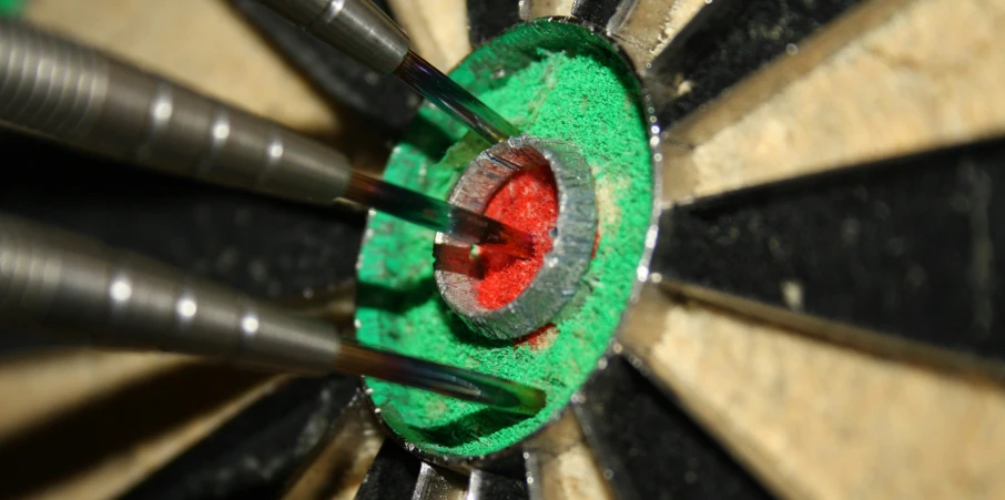 three darts are pointed into the center of a round with a green surface