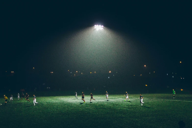 several soccer players are kicking around at night